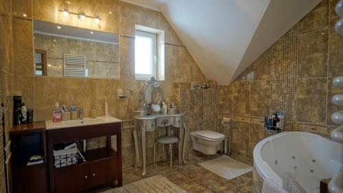 uma casa de banho com uma banheira, um lavatório e um WC. em Willa Raj - Apartamenty nad jeziorem KA-BOATS em Rajgród