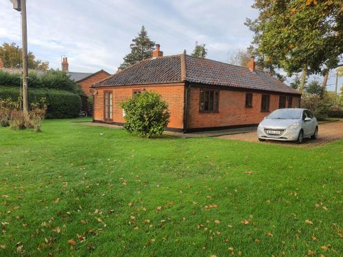 a car parked in front of a brick house at Cosy Rural Barn Conversion 5 Min Drive To Pin Mill 1 BR + sofa bed in Chelmondiston