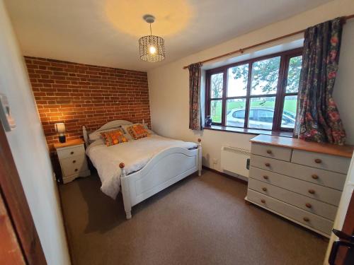 a bedroom with a bed and a brick wall at Cosy Rural Barn Conversion 5 Min Drive To Pin Mill 1 BR + sofa bed 