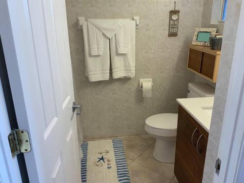 a bathroom with a toilet and a sink with towels at Comfy Coastal Beach Vacation in Clearwater Beach