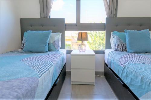 um quarto com 2 camas com almofadas azuis e uma janela em Fantastic 2 bed apartment in modern complex in Pilar de la Horadada em Pilar de la Horadada