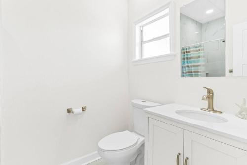 a white bathroom with a toilet and a sink at Dolphin Watch in Clearwater Beach