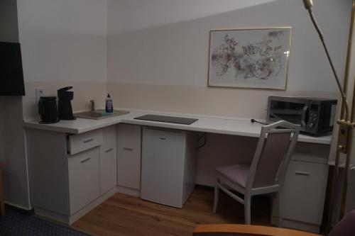 a kitchen with a desk with a microwave and a chair at Gästehaus Wacholderheide Garni in Eimke