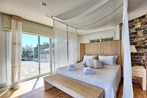 a bedroom with a bed and a large window at Villa Marina by PosarelliVillas in Elounda