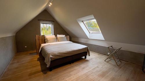 a attic bedroom with a bed and two windows at La ferme du Comte in Durbuy