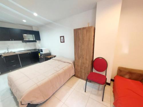 1 dormitorio con 1 cama y 1 silla roja en Apartaestudio Laureles la 33, en Medellín