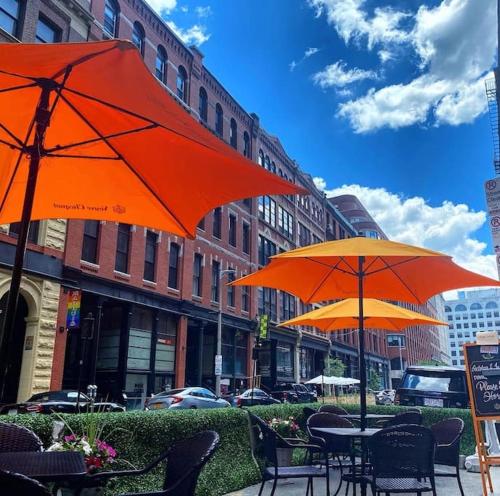 dwa stoły z pomarańczowymi parasolami na ulicy miejskiej w obiekcie Beach Street Loft w mieście Boston