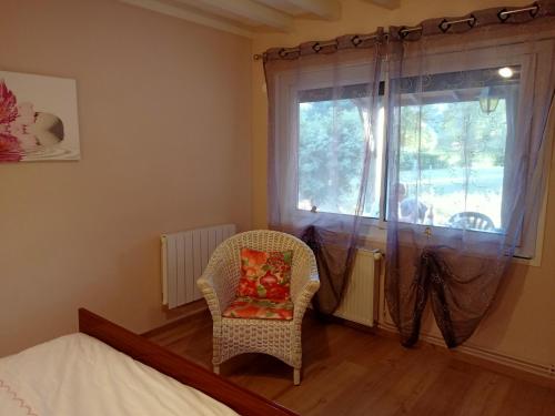 a bedroom with a bed and a chair and a window at Gîte A-B Roger in Ganties