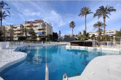 a large swimming pool with palm trees and buildings at Luxury apartments Alamos beach Torremolinos - Costa Lago in Torremolinos