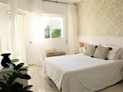 a white bedroom with a white bed and a window at Luxury apartments Alamos beach Torremolinos - Costa Lago in Torremolinos