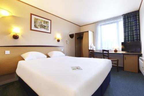 a hotel room with a large white bed and a desk at Campanile Hotel - Washington in Washington