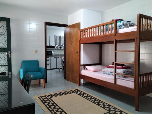 a bedroom with two bunk beds and a blue chair at Pousada Casa Verde - Curitiba in Curitiba