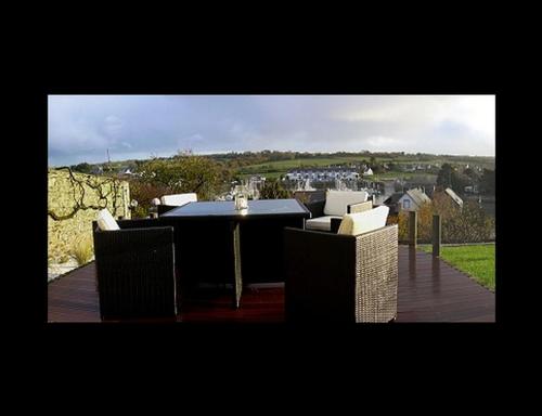 a table and chairs sitting on a deck with a view at Studio de Charme "Le Coquillage " Jacuzzi privatif in Pléneuf-Val-André