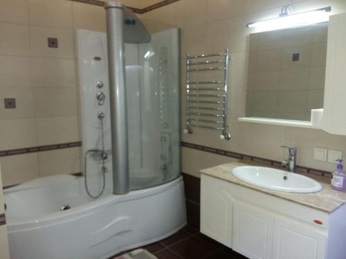 uma casa de banho com um chuveiro, um lavatório e uma banheira em Апартаменты на набережной с панорамным видом на 39 этаже em Astana