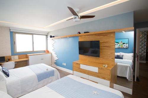 a hotel room with two beds and a tv at Barra da Tijuca de frente para o mar - 2 suítes até 6 pessoas em camas in Rio de Janeiro