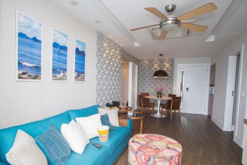 a living room with a blue couch and a ceiling fan at Barra da Tijuca de frente para o mar - 2 suítes até 6 pessoas em camas in Rio de Janeiro