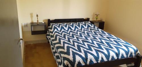 a bedroom with a bed with a black and white comforter at Don Marcos - Las Estancias de Aconquija in Cochuna