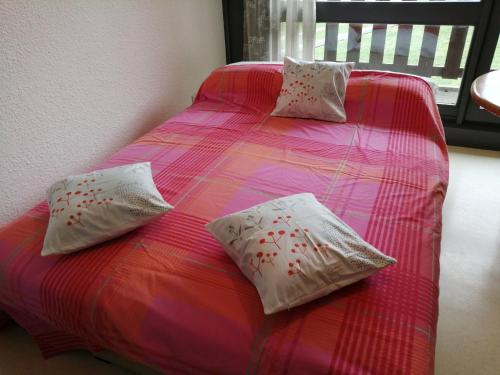 Una cama rosa con dos almohadas encima. en petit nid montagnard, en Rousset