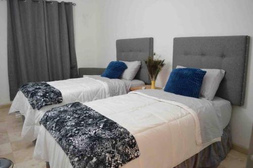 twee bedden met witte en blauwe lakens in een kamer bij Disfruta un agradable alojamiento en Rocky Point in Puerto Peñasco