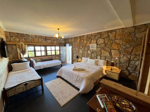 a bedroom with two beds and a stone wall at Rise In Valley in Ifrane