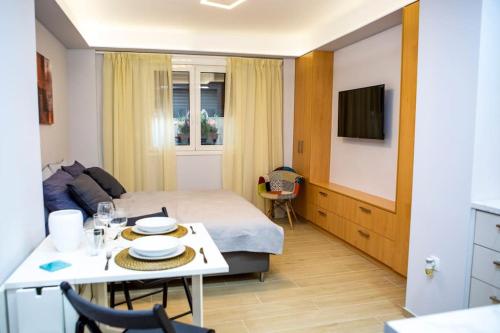 アテネにあるStudio apartment with all amenities in Kolonakiのベッドとテーブルとテレビがあるホテルの部屋