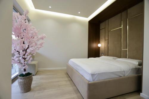 Un dormitorio con una cama blanca y un árbol en La Grand - New Bazaar, en Tirana