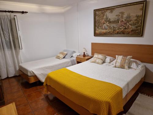 a bedroom with two beds and a painting on the wall at Casa Dos Santos Alojamento - Guest House in Geres