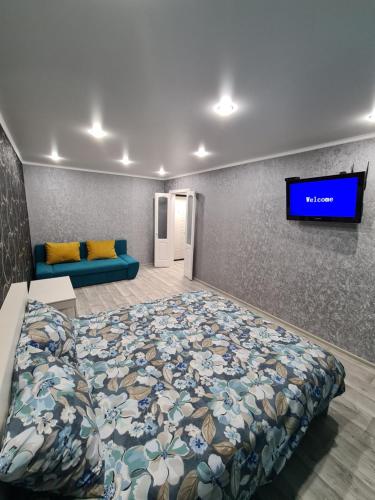 a bedroom with a bed and a tv on a wall at Однокомнатная квартира в центре Петропавловска in Petropavlovsk