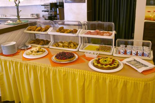 a table with plates of food on a yellow table at Hotel al Corso in Legnano