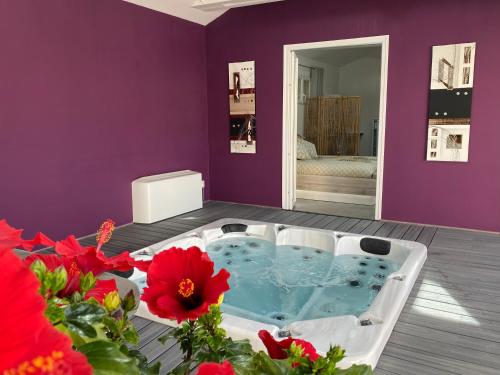 uma banheira de hidromassagem num quarto com flores vermelhas em Le SPA de l Albizia em Cessieu