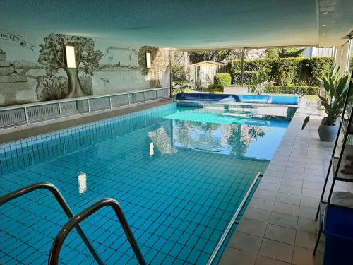 a large swimming pool with blue tiles in a building at Hotel Garni La mer in Bad Zwischenahn