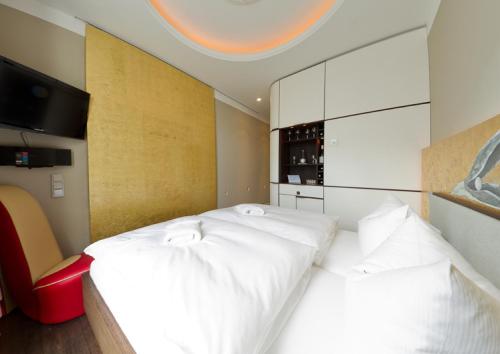 a bedroom with two white beds and a red chair at Ringelnatz Warnemünde in Warnemünde