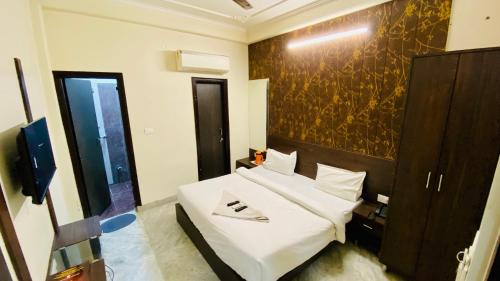 a bedroom with a white bed and a wall at Hotel Pulse Inn- Near Jaipur Railway Station in Jaipur