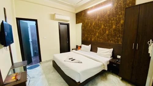 a bedroom with a large white bed and a tv at Hotel Pulse Inn- Near Jaipur Railway Station in Jaipur