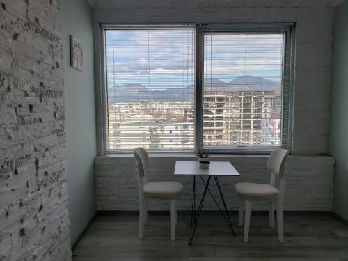 1 mesa y 2 sillas en una habitación con ventana en Agroni Rooms, en Tirana