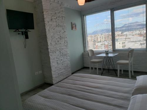 Habitación con cama y mesa con sillas. en Agroni Rooms, en Tirana