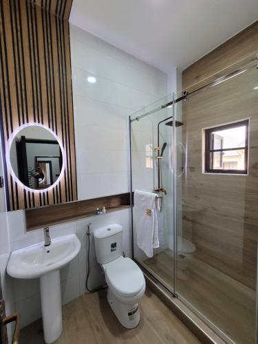 a bathroom with a toilet and a sink and a mirror at The Charis Hotel & Suites in Port Harcourt