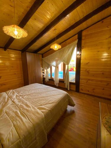 a bedroom with a large bed in a room with wooden walls at بلفيو كوخ in As Sayl aş Şaghīr