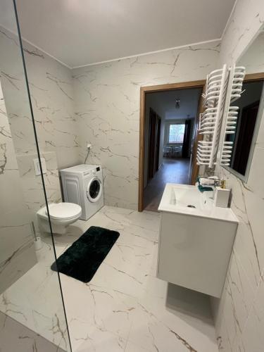 a bathroom with a toilet a sink and a washing machine at Apartament Wierzbowa Park in Białystok