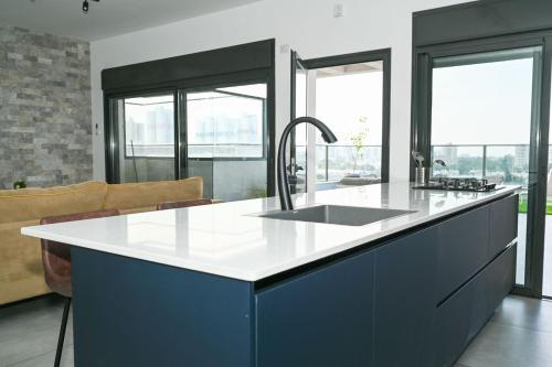 a kitchen with a sink and blue cabinets at Luxurious penthouse for couples in Kiryat Mozkin in Qiryat Motzkin