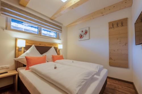 a bedroom with a large white bed with orange pillows at Chalets AurAlpin in Kleinarl