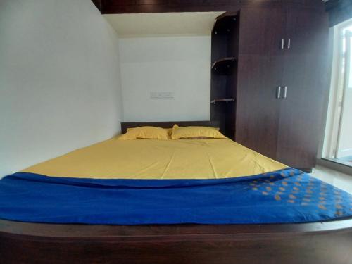 Una cama en una habitación con una manta azul. en JEENA MOTEL, en Kollam