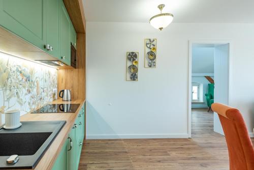 a kitchen with green cabinets and a hallway at Dworek Wojanów in Wojanów