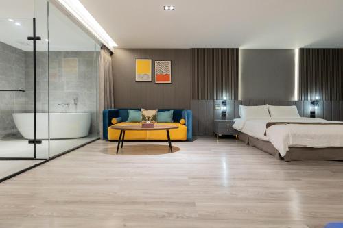 a bedroom with a bed and a bath tub next to a bed and a table at Hualien Pink Corner Hotel in Hualien City