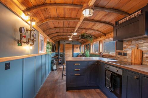 a kitchen with blue cabinets and a wooden ceiling at Appin Holiday Homes -Caravans, Lodges, Shepherds Hut and Train Carriage stays in Appin