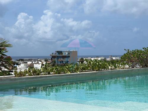 een zwembad met een blauwe parasol naast een gebouw bij Anah Downtown luxury condo in Playa del Carmen
