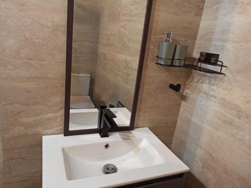 uma casa de banho com um lavatório branco e um espelho. em Beautiful Studio apartment in Qormi Malta em Qormi