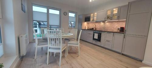a kitchen and dining room with a table and chairs at Urokliwy Apartament Bałtyk 2 nieopodal Gdyni NEW in Pogórze