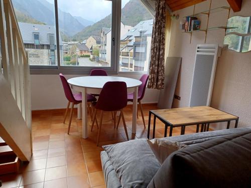 a living room with a table and chairs and a window at Moudang 11 in Saint-Lary-Soulan