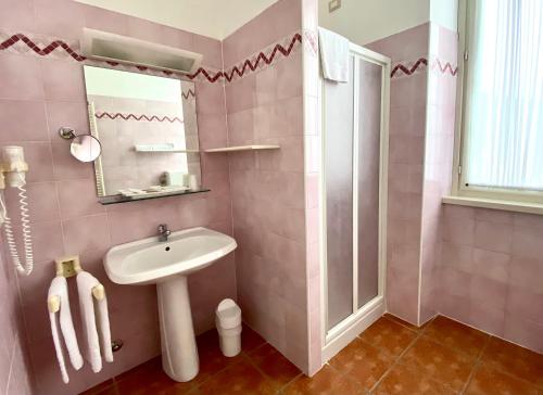 a pink bathroom with a sink and a mirror at Caroline Hotel in Brusimpiano